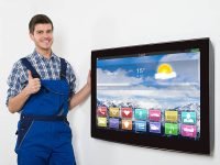 Happy Male Technician Standing Near Television Gesturing Thumb Up